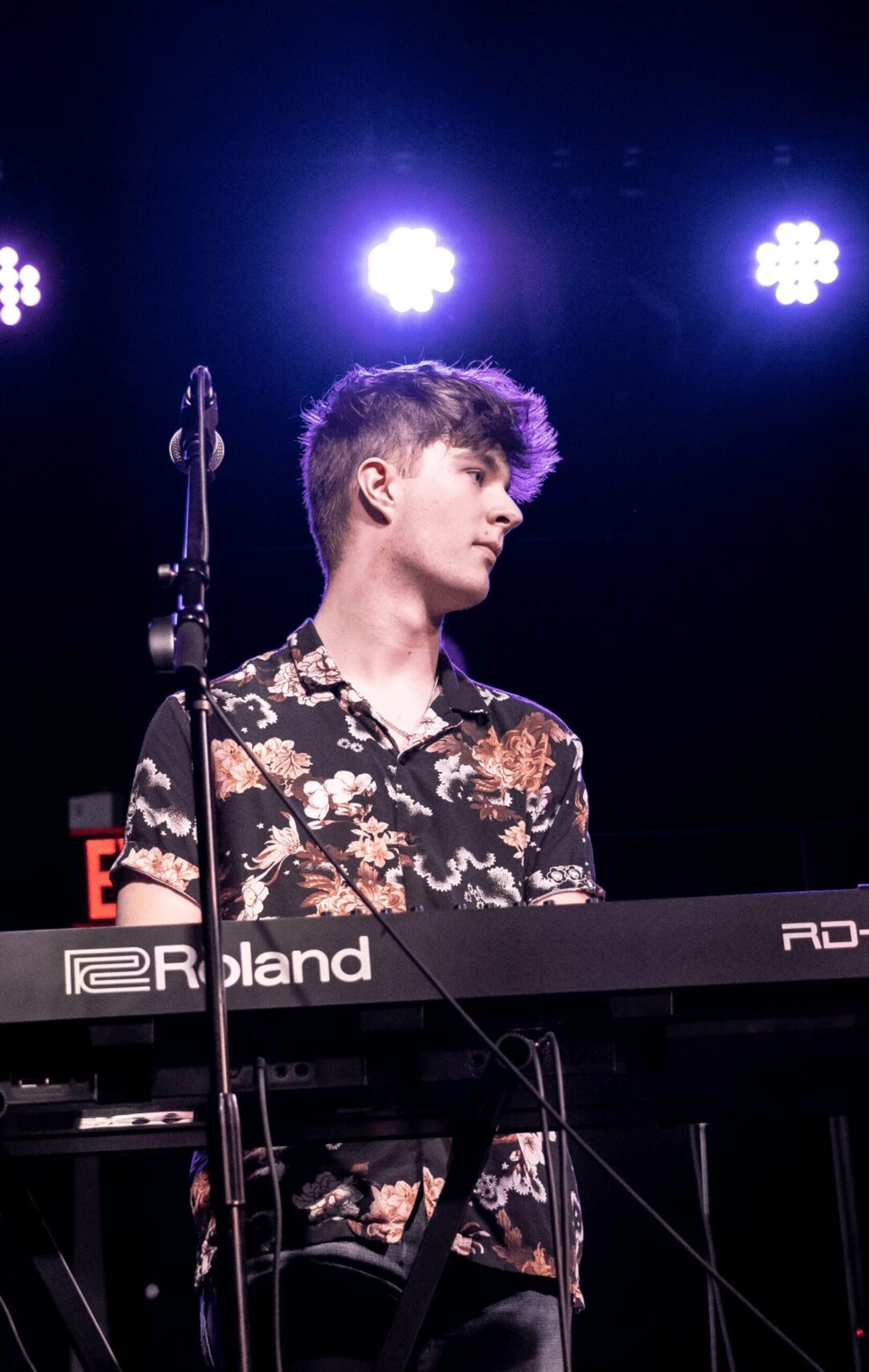 Colman Connolly performing on keyboard under stage lights